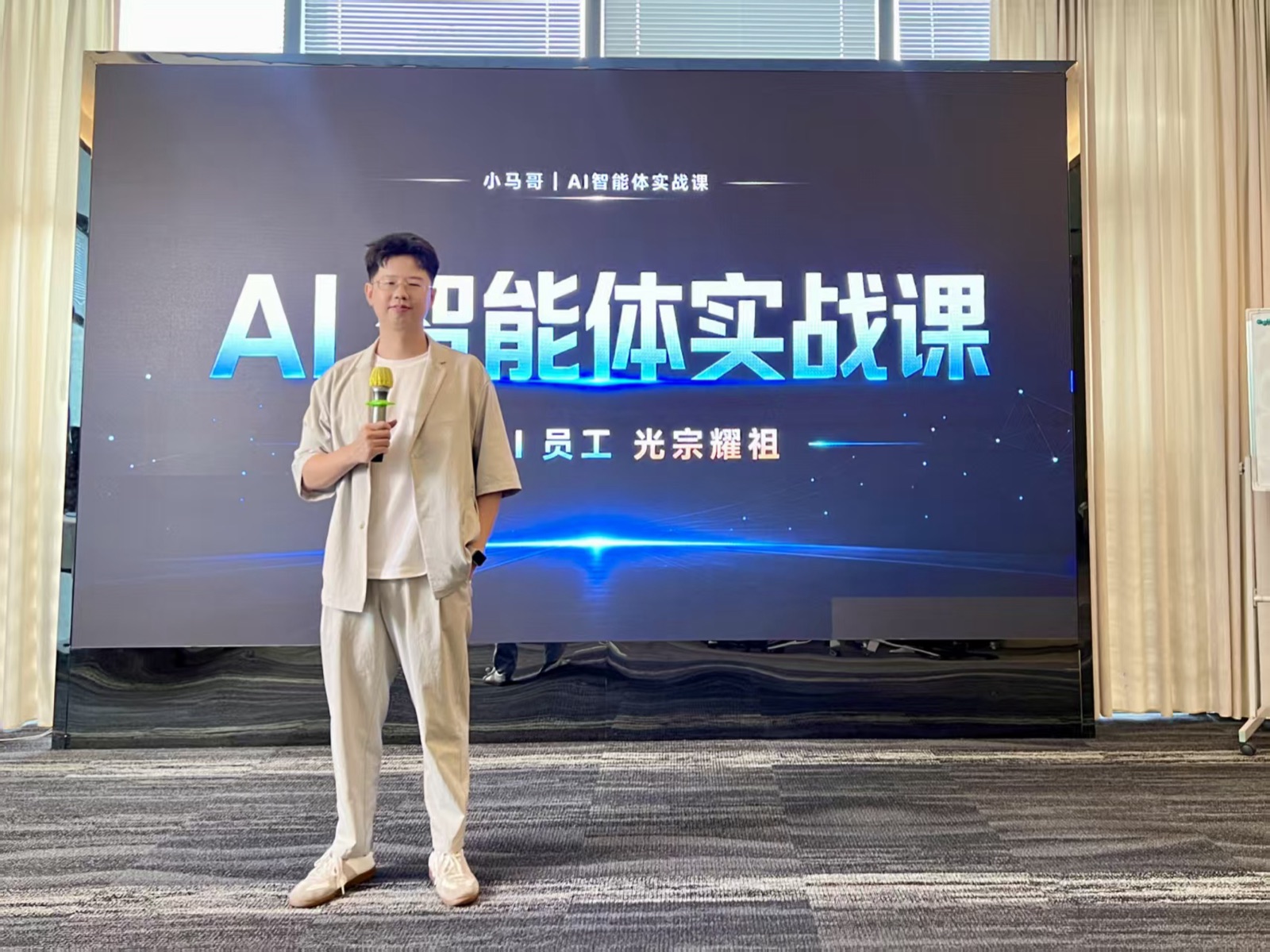 小马哥在AI智能体实战课培训现场，手持麦克风站在大屏幕前